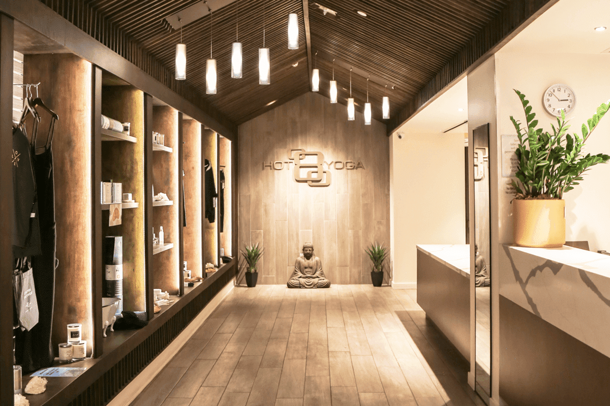 Modern hot yoga studio interior with Buddha statue and retail shelves